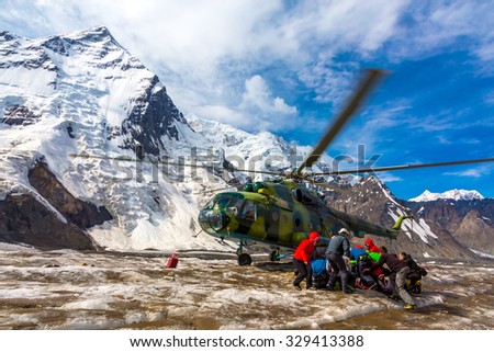 Transport Helicopter Taking Off from Ice Field of Massive Mountain Glacier People Holding Luggage to Protect from Wind Blowing of Rotor