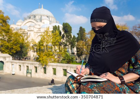 Middle Eastern Woman drawing Sketch of Architecture Attraction in Paper Notepad with Pencil sitting