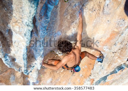 Top View of Rock Climber on orange Vertical Wall naked Torso ascending