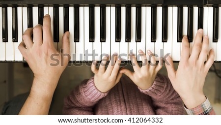 Family Unity Concept Image - Piano Keyboard top View and Hands of Child Mother and Father playing music