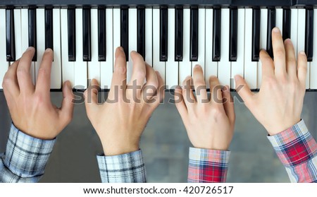 Teamwork Concept Image - top View of Piano Keyboard and male and female Hands playing music together four handed