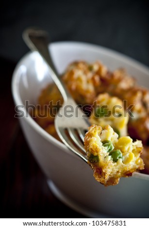 Corn and Pea fritters on a fork in white bowl