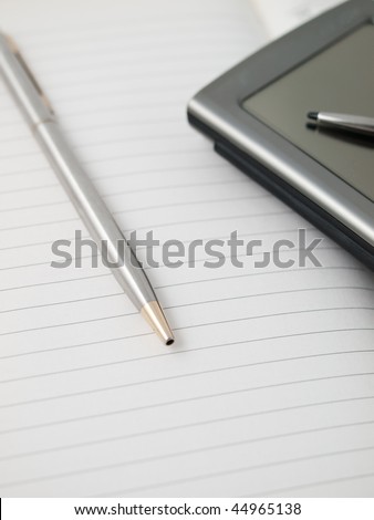 A pen and a pda on a notebook ready to take notes