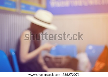 Blurred image of asian woman use smartphone and waiting for the bus at bus terminal , vintage color