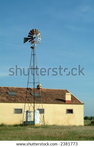 Windmill pump and barn against the sky in farm