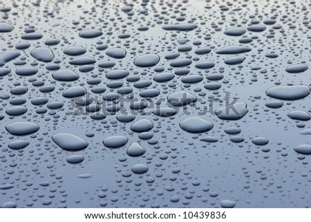 Water drops in blue reflected metallic surface