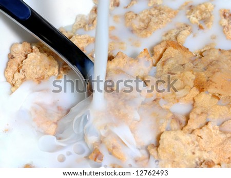 Milk pouring into a bowl of cereal corn flakes
