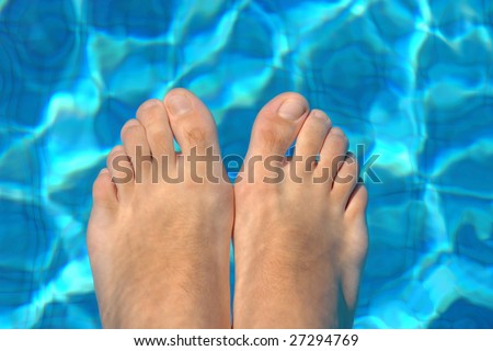 Underwater feet in blue water on swimming pool