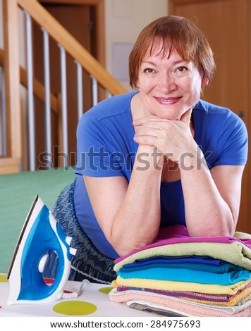 Happy  woman ironing at ironing board in home