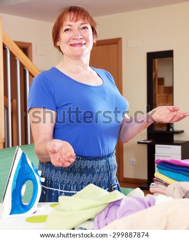 Happy woman ironing clothes on an ironing board