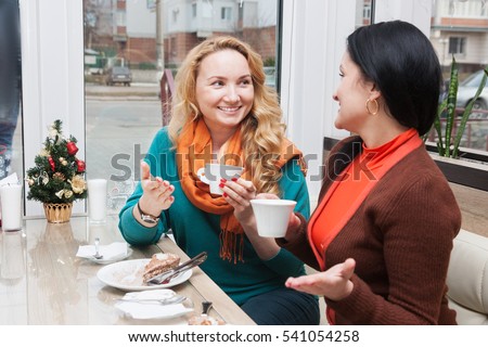 Young women talking and drinking coffee in a small cafe