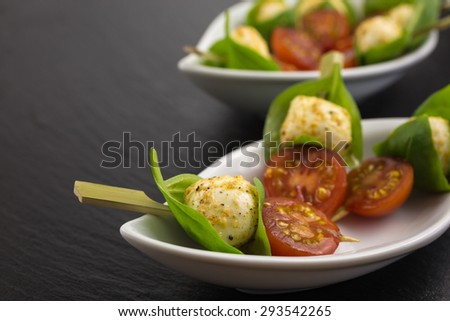 mini mozzarella ball in a basil leaf, marinated in pepper, lemon and olive oil with cherry tomato