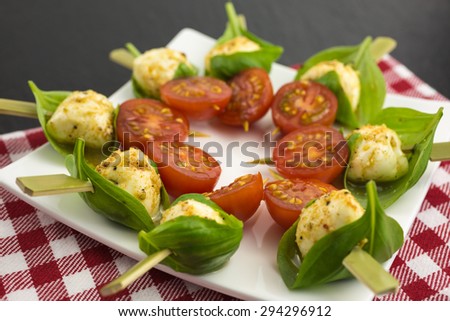mini mozzarella ball in a basil leaf, marinated in pepper, lemon and olive oil with cherry tomato