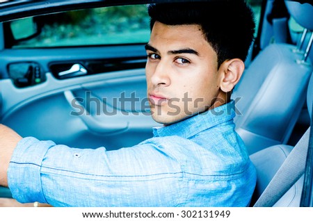 Young handsome adult sitting in expensive car