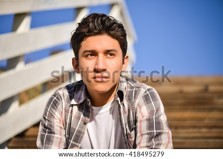 Young man thinking outside. Sitting on steps, looking into the distance