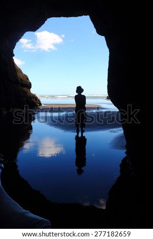Figure silhouetted in cave entrance