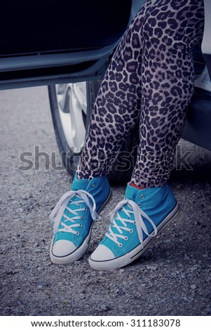 The woman rising out of the car with blue sneakers in Finland. He is wearing a leopard-print pants. Image includes a winter effect.