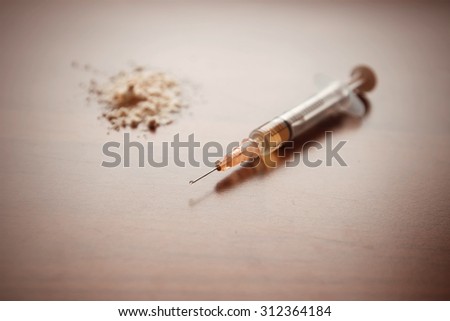 Injection syringe, and in the background a pile of white flour. Images of drug needles and drug. The picture is staged and there is no real drugs. Image includes a Autumn effect.