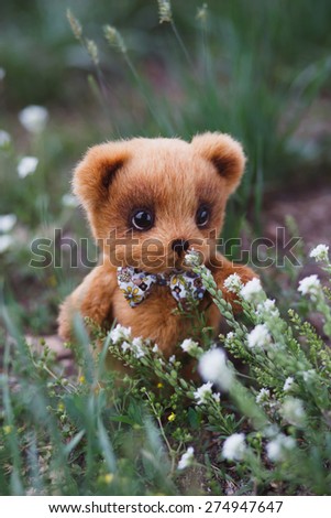 Brown artist Teddy bear with bow tie in flower garden