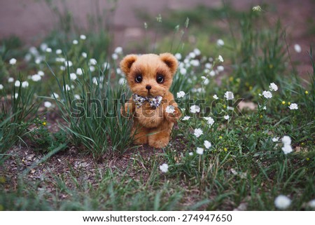 Brown artist Teddy bear with bow tie in flower garden