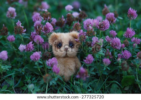 Brown artist Teddy bear in violet flower garden