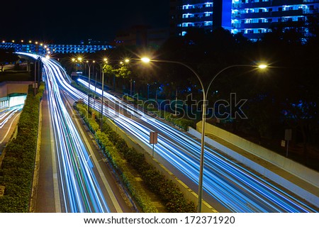 Singapore, Singapore - December, 21: Light trails on Singapore roads with high rise buildings taken at night on December 21, 2013