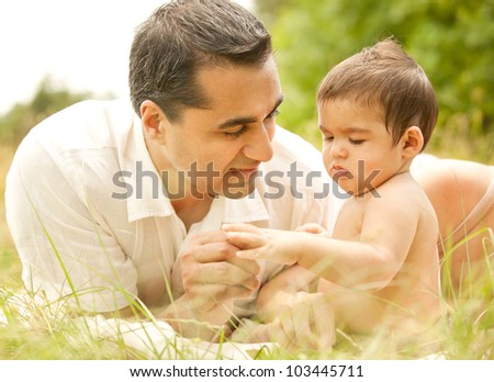 Smiling Indian Father with Baby Son Outdoors on Grass