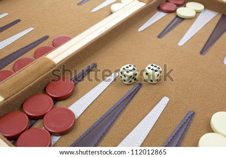 Two dice with several pieces at angle of backgammon game.