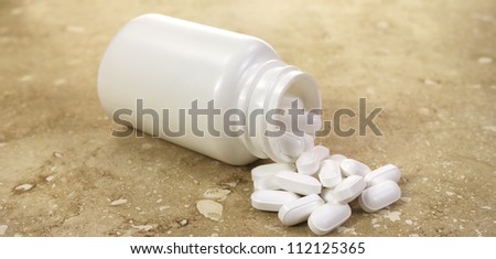A plastic bottle with several potassium gluconate tablets spilling onto a marble surface.