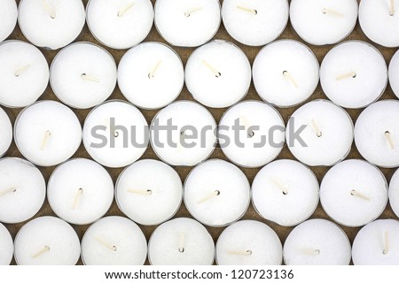 Top view of rows of white wax tea light candles.