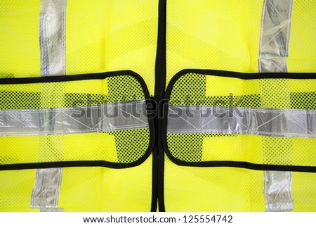 A very close view of a florescent yellow safety vest with silver reflective stripes.
