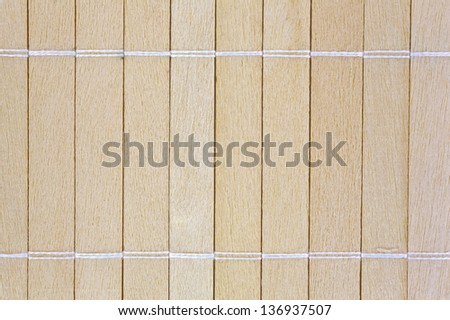 A very close view of small wood slats that have been joined together with string.