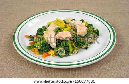 A single serving of salmon with carrots and spinach on pasta TV dinner on a plate.