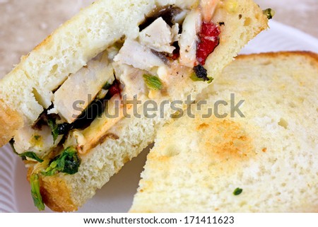 Close view of a chicken sandwich that has been cut in half on a small plate.