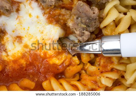 Close view of an Italian sausage with pasta in tomato sauce TV dinner with fork.