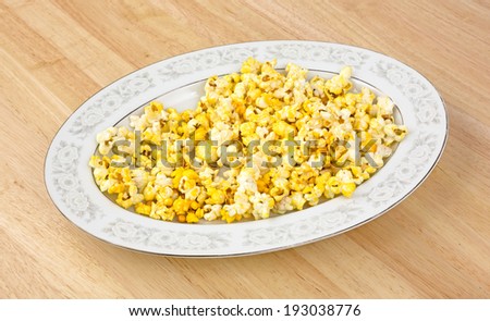 An oval platter of popcorn on a dining room table.