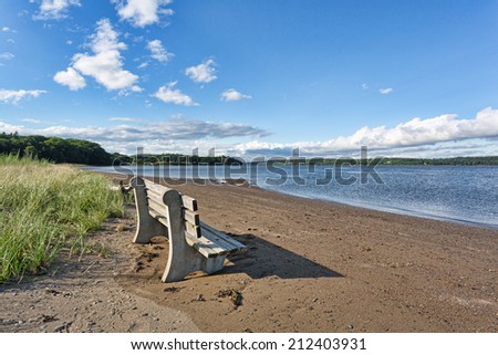 An old concrete and wood bench at Sandy Point Beach facing the Penobscot River in Stockton Springs, Maine