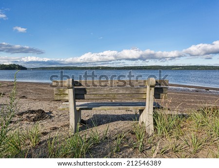 An old wood and concrete bench facing the Penobscot River at Sandy Point Beach in Stockton Springs Maine.
