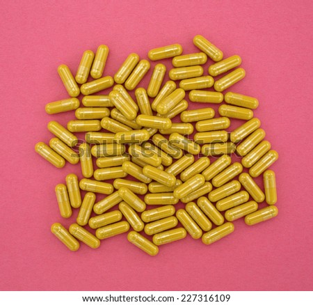 A group of turmeric herbal capsules on a red background.