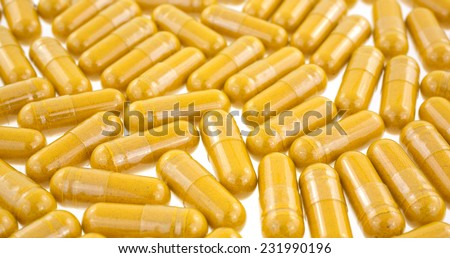 A layer of turmeric herbal capsules on a white background.