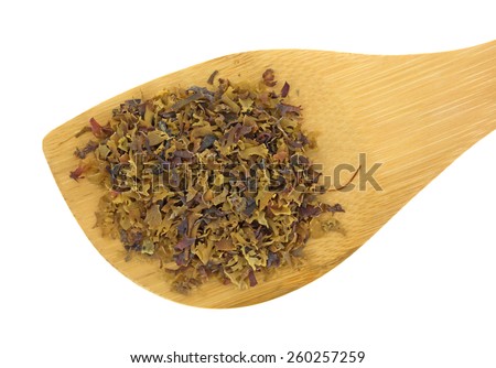 Top close view of a wood spoon with a portion of Irish moss flakes on a white background.