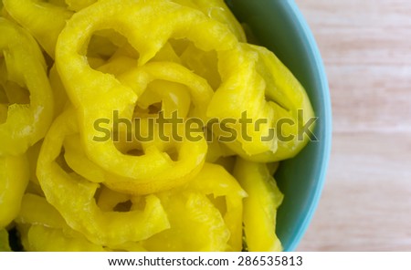 Close top view of crinkle cut banana peppers on a wood table top illuminated with natural window light
