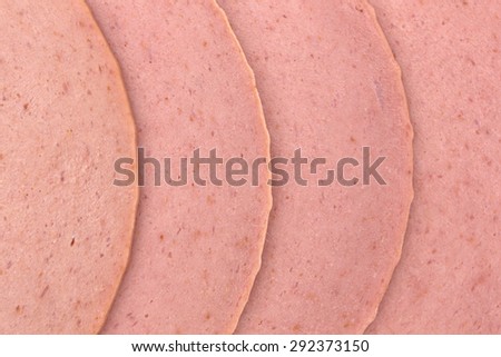 A close view of several slices of bologna in a row.