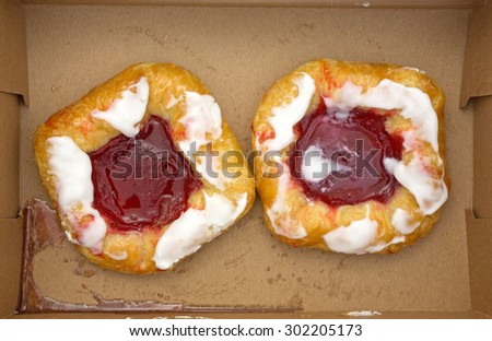 Top view of two raspberry danish pastries in a cardboard box.