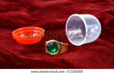 Vending machine jewelry ring with plastic container on a red velvet background