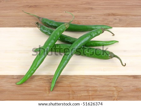 Long green hot peppers on wood cutting board