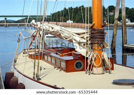 The clean deck of a small sailboat with mast and rigging.