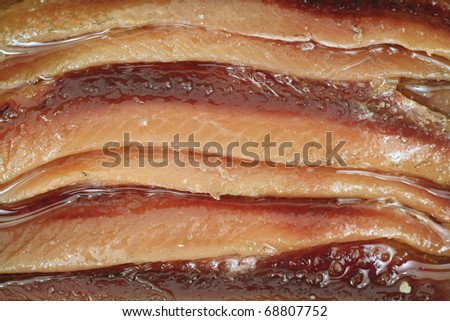 Closeup of flat filleted anchovies in soybean oil.