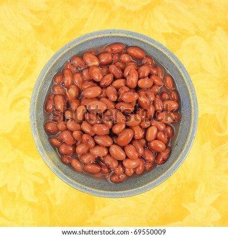 A large serving of pink beans in a bowl on a yellow floral pattern cloth.