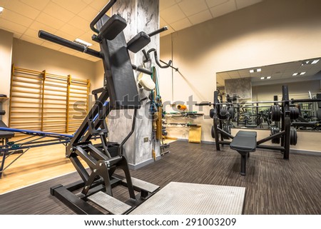 Panoramic interior view of modern equipment in the gym with mirrors on the walls, machines for sport, fitness and wellness.